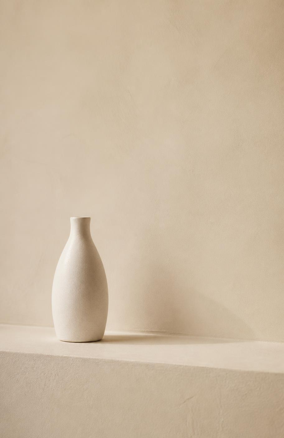 Sculptural oak and stone objects against an ivory plaster wall